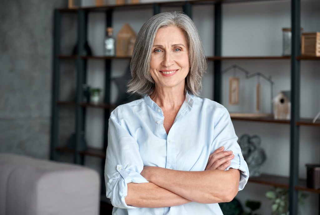 Smiling older woman at home with arms crossed, illustrating how to sell a mortgage note with confidence